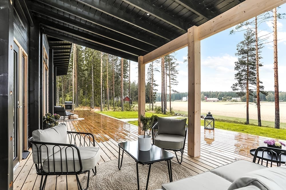 Ett svart timmerhus i lantlig miljö