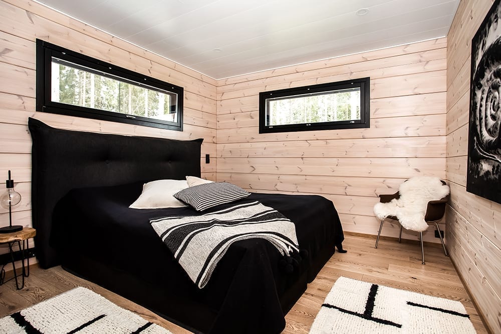 Ett svart timmerhus i lantlig miljö