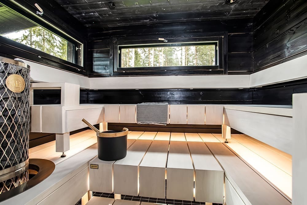 Ett svart timmerhus i lantlig miljö