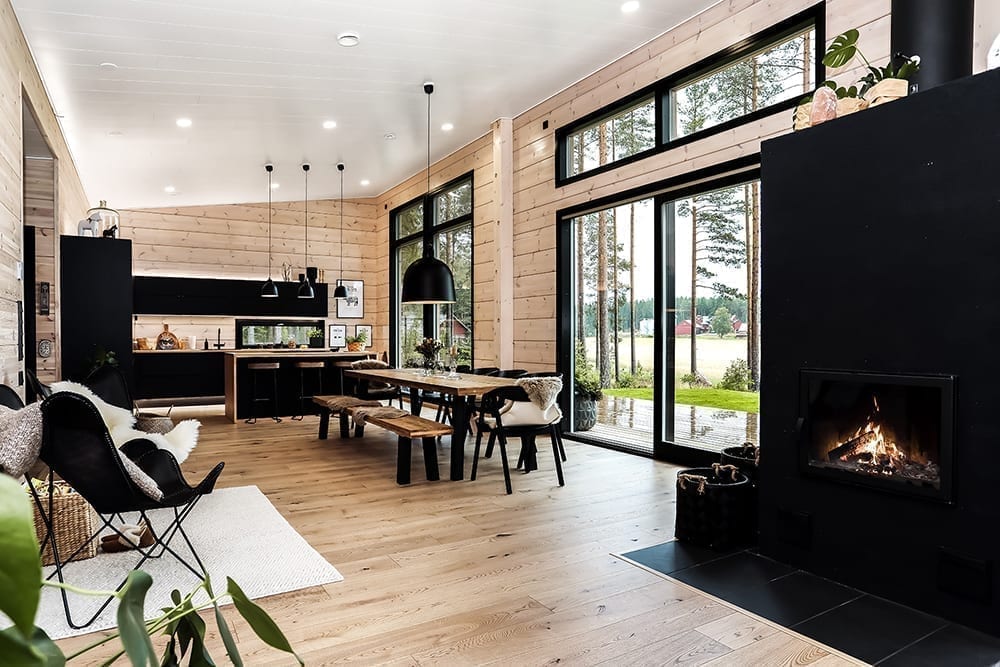 Ett svart timmerhus i lantlig miljö