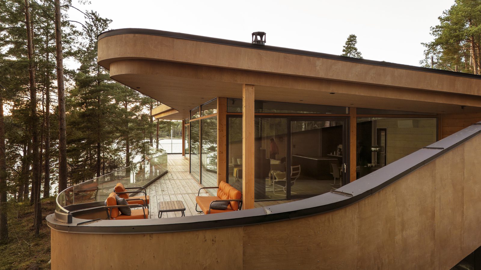 Contemporary log home interior with floor‑to‑ceiling windows and natural wood surfaces, opening to forest views.